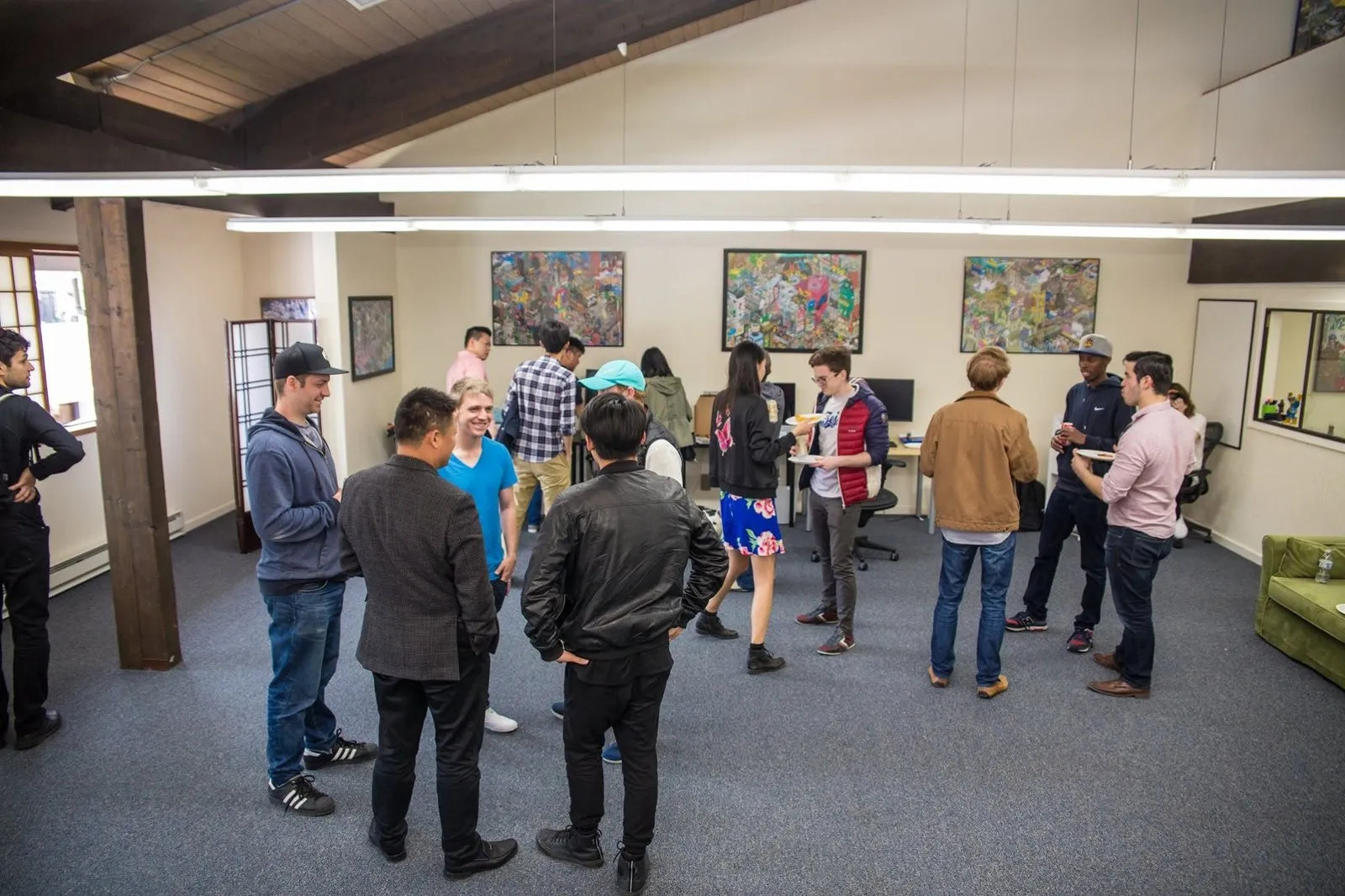 A gathering in a loft office with exposed beams, pixel-art posters on the wall and a shoji screen in the corner