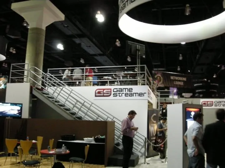 The two-storey GameStreamer booth on the show floor at E3 2010, with a staircase up to a meeting deck